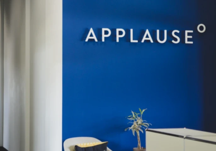 Applause logo on a dark blue wall in an office