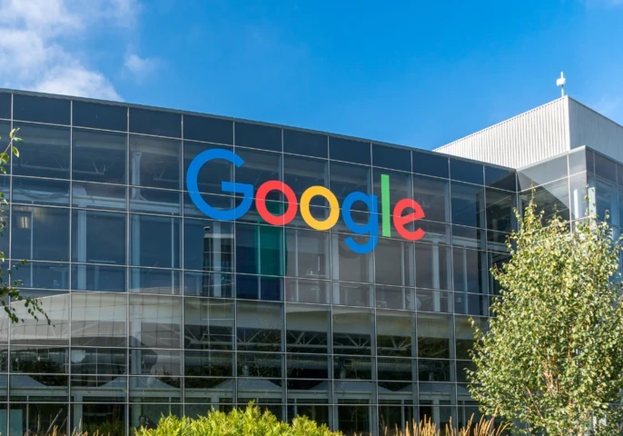 Google logo on the side of a building with lush greenery in front of it.