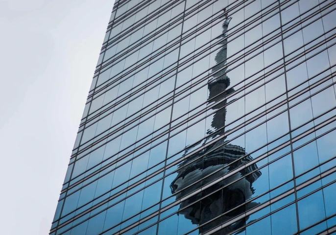 A tower's warped reflection in the window's of a skyscraper showing corruption and scandal underneath a perfect veneer.