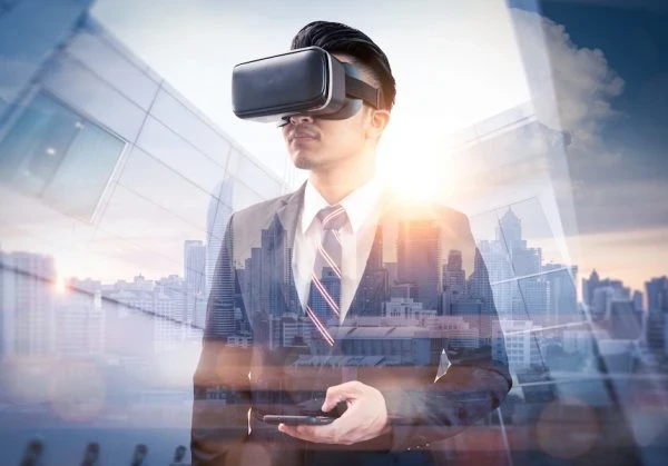 A businessman wearing virtual reality glasses and handling a smartphone against a cityscape.