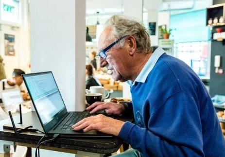 An elderly man sitting in front of a laptop.