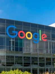 Google logo on the side of a building with lush greenery in front of it.