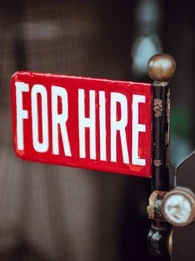A close-up of a "for hire" sign on an old-fashioned machine.