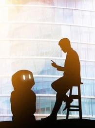 A photo of a person giving a robot instructions while the robot looks up at the person