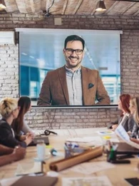 People sitting at a desk looking up at at video conferencing screen.