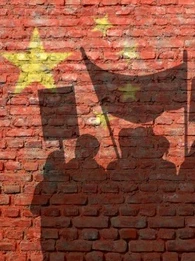 A shadow of a protesting crowd with banners against a brick wall with the EU logo on it in yellow