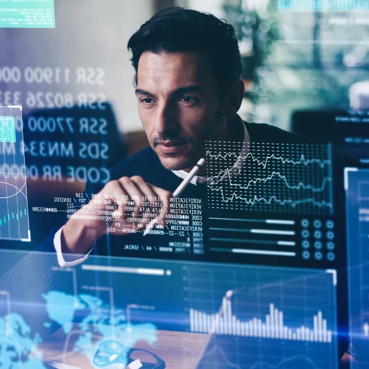 A man sitting in front of a transparent screen with code and graphics on it.