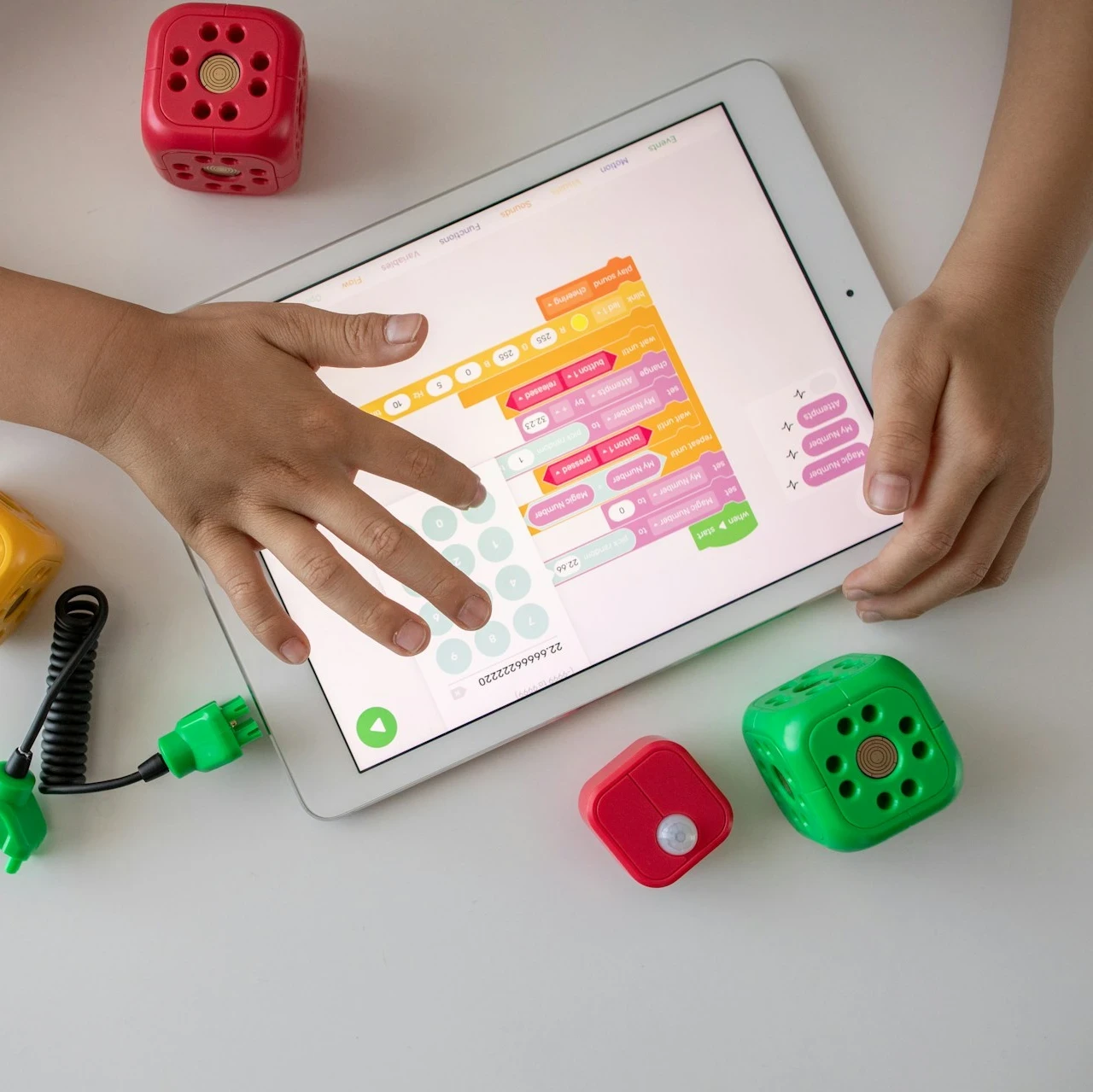 A child learning on a tablet with toys laying all around them.