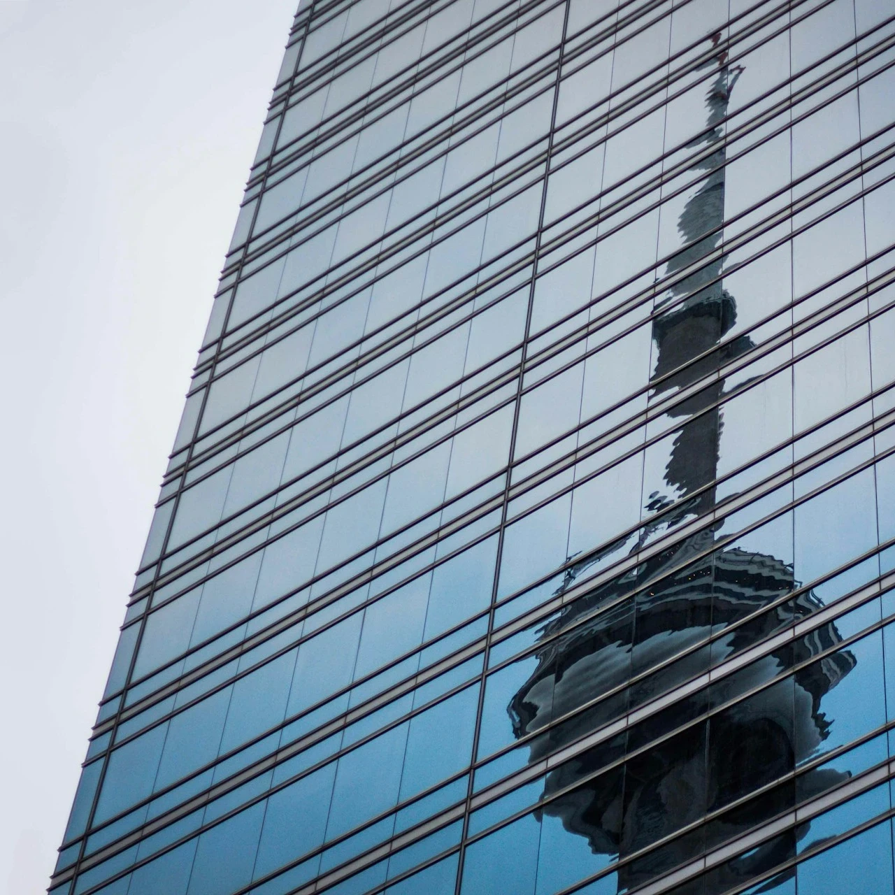 A tower's warped reflection in the window's of a skyscraper showing corruption and scandal underneath a perfect veneer.
