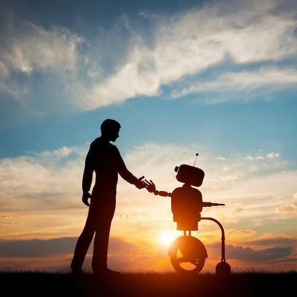 A person shaking hands with a robot with a sunset in the background.