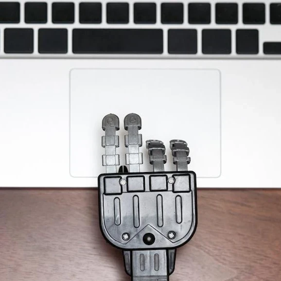 Robot hand using a trackpad on a laptop.