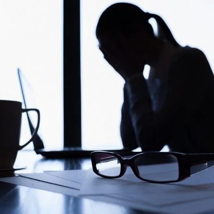 Woman sitting at a desk with her head in her hands.