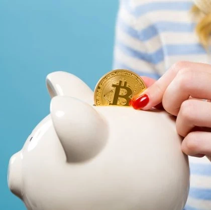 Woman placing a Bitcoin coin into a piggy bank.